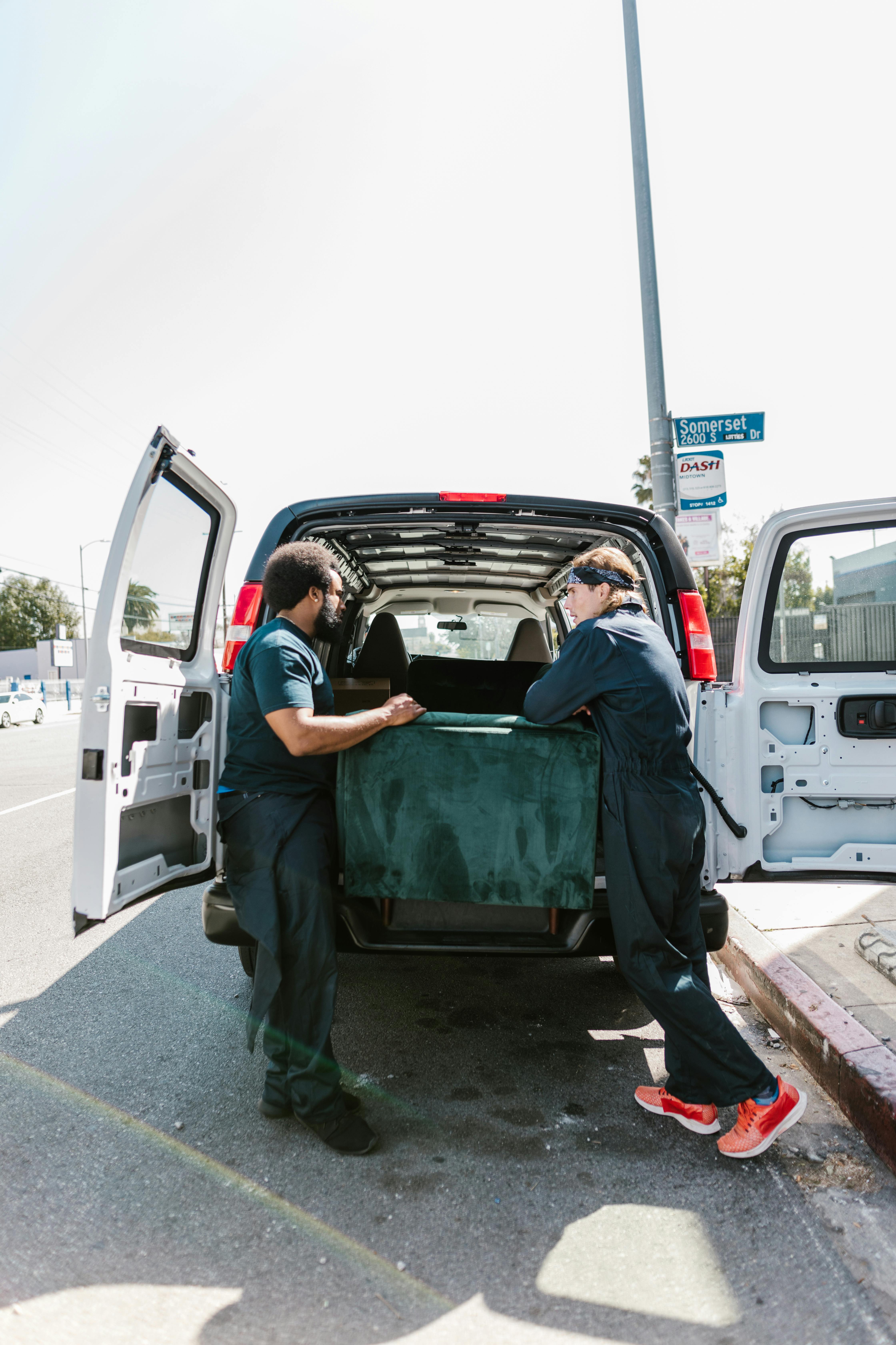 Two movers lifting a large item into the back of a van