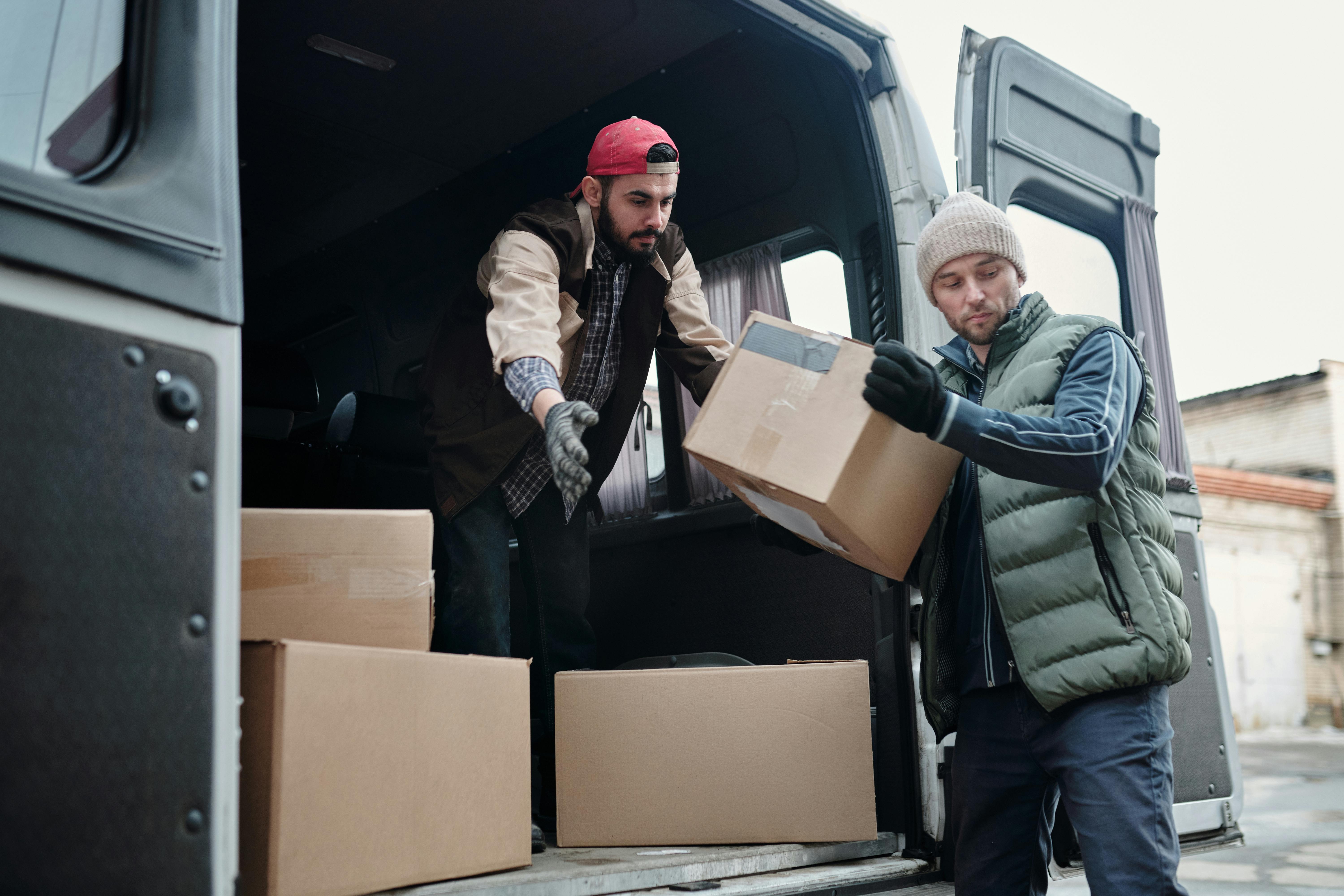 Two movers unloading cardboard boxes from a van